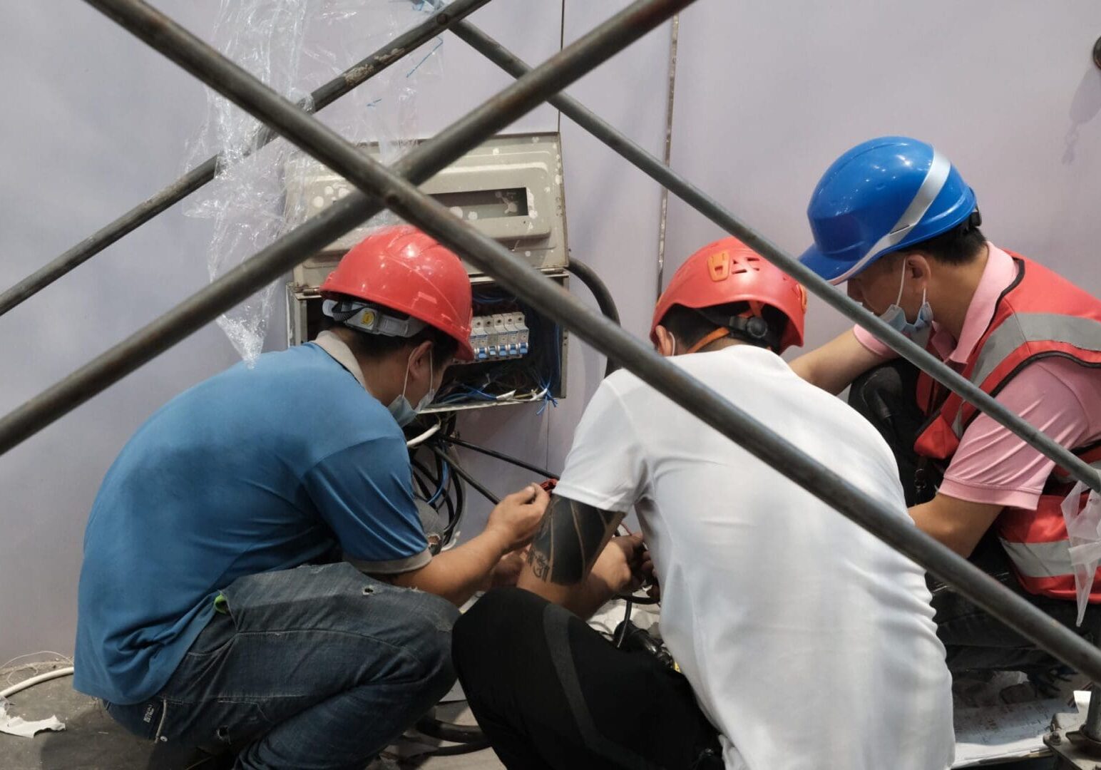 Three electricians repairing a utility panel